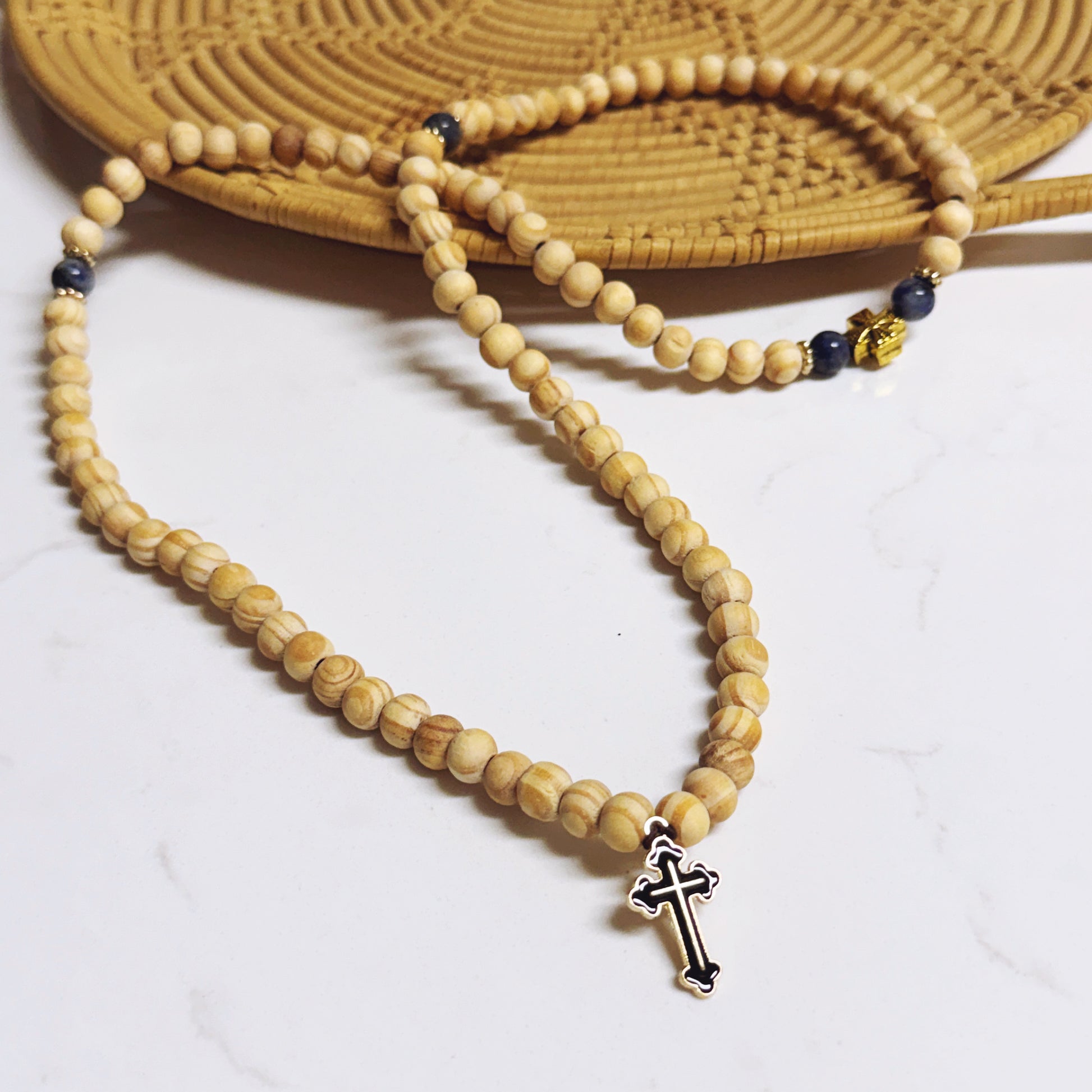Wooden beaded necklace with a cross pendant on a white surface